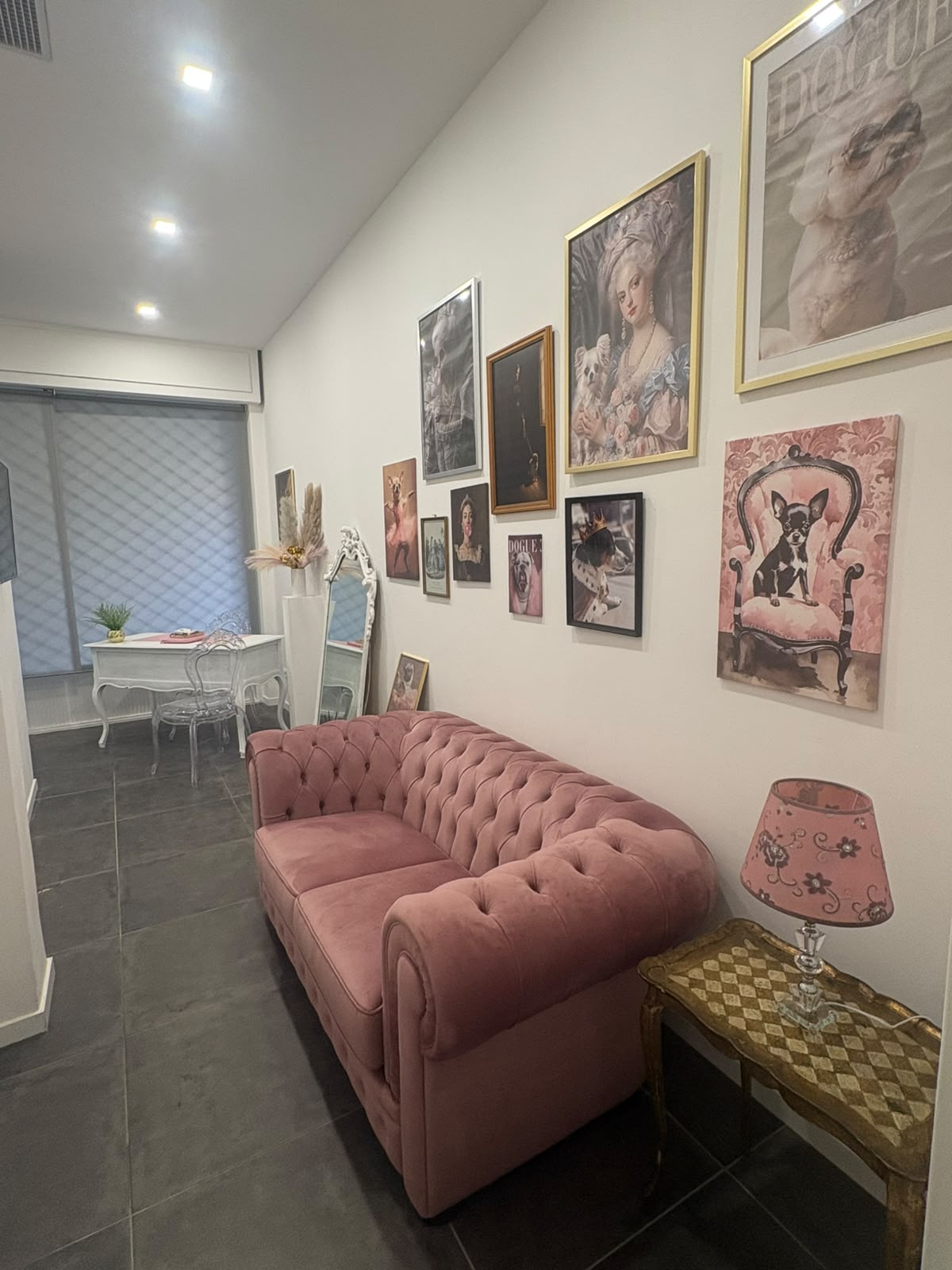 Divano Chesterfield rosa sotto una parete di quadri di chihuahua
